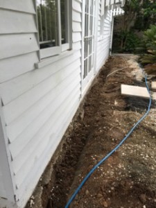 Trench prepared for a termite chemical barrier beside a house